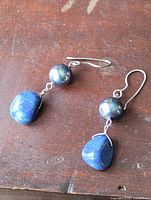 Earrings laid flat showing lapis drops, round beads, hooks