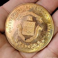 Obverse of bronze medallion showing coat of arms, Outstanding Achievement Award text and maple leaves