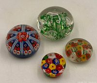 Four Murano paperweights grouped together showing variety of designs and sizes