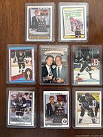 Eight hockey cards in sleeves laid out on wooden surface