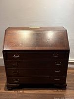Front view of closed mahogany secretary desk showing four drawers and slant top