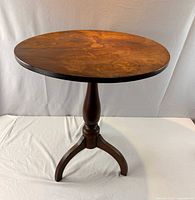 Full view of round tilt-top table showing top, pedestal and tripod base