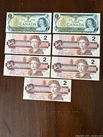 Fronts of two 1973 $1 notes and five 1986 $2 notes