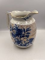 Front view of ceramic pitcher showing floral design and gilt rim
