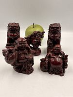 Five figurines including pair of guardian lions and three laughing Buddhas with apple for scale
