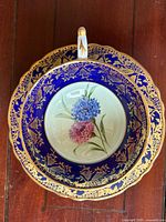 Teacup nested in saucer showing cobalt blue and gold filigree with hydrangea motif
