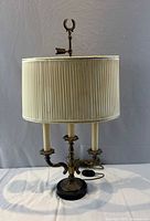 full view of brass bouillotte lamp with pleated shade
