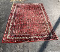 Full view of rectangular red Persian rug laid flat outdoors
