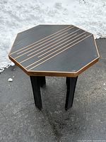 Full view of octagonal table showing top surface, copper-tone inlays and edge band, four legs