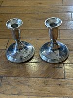 Pair of candlestick holders standing upright on wooden floor