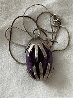 Necklace coiled showing pendant front on white cloth background