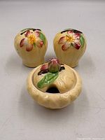 Front view of three ceramic pieces showing hand-painted blossom tops