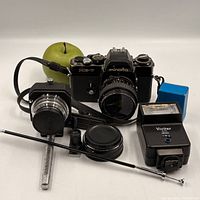 Group shot of all items in lot: camera with lens, flash, turret finder, adapter body, eyepiece, metal box, strap, cap