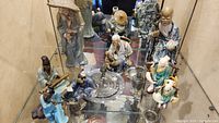 Group view of all eight Mudman figurines on glass shelf