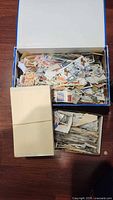open cardboard box filled with loose stamps and additional small box and stock cards visible