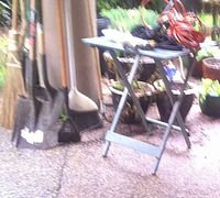 Group of long-handled tools leaning together beside broom