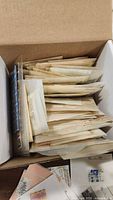 Cardboard box filled with many glassine envelopes containing stamps