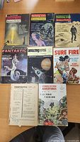 Group of seven assorted magazines and paperbacks on tabletop