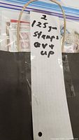 Bag containing zipper bags of assorted stamps with handwritten weight note visible