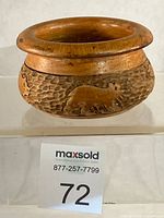 Overall view of carved wooden bowl showing bear motif and texture