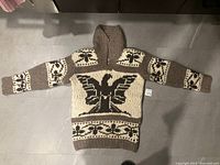 Full view of sweater laid flat showing overall design and dimensions tag visible