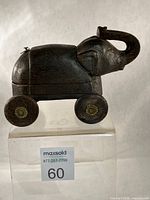 Full side view of wooden elephant box on clear stand showing wheels and trunk