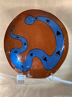 Front view of red earthenware platter with blue rattlesnake design