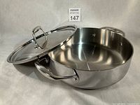 Saucepan with lid partially open showing interior and side handles