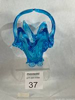 Front view of ice blue Chalet art glass basket with twin handles and footed base