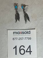 Pair of silver feather earrings with turquoise stones, front view with lot card