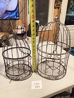 Both metal bird cages side by side with measuring tape for scale