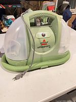 Front view showing Bissell Little Green unit with hose and carry handle