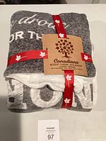 Front view of folded Canadiana accent throw with ribbon and label visible