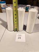 Front view of three white candles next to tape measure showing height