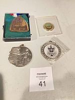 Overview of all four medals: Olympic Festival medal in case, gold-tone token in flip, silver-tone Indigenous scene medal, Ottawa Senators medal