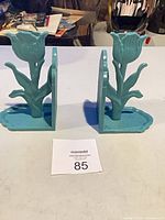 Front view of teal cast iron tulip bookends on table