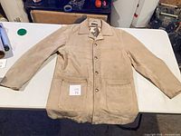 Full front view of beige suede Gianni jacket on table