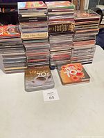 Wide shot showing multiple stacks of CDs on table with two Hits of the 70s tins in foreground