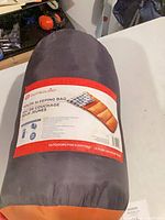 Rolled sleeping bag in stuff-sack with brand label visible