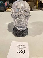 Front view of clear skull on dark pedestal