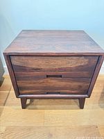 Front view of nightstand showing two drawers, integrated pulls, tapered legs