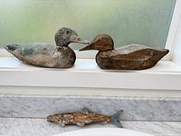 Two duck decoys and one fish decoy displayed together