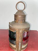 Front view showing both red and green lenses, metal body, ring handle, vented chimney