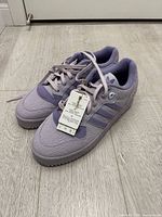 Pair of lilac Adidas Rivalry Low sneakers front three-quarter view with tags