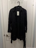 Front view of black Zara sateen shirt dress on hanger showing overall style and tie belt