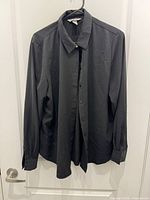 Front view of black collared shirt showing button placket and sleeves