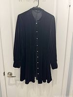 Front view of black velour button‐up dress on hanger showing jeweled buttons and overall style
