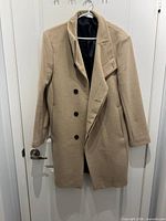Front view of camel coat on hanger showing buttons and collar