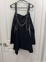 Front view of Killstar black chain harness dress on hanger showing chains and asymmetrical hem
