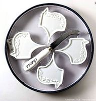Set in box showing four white ceramic markers and cheese knife